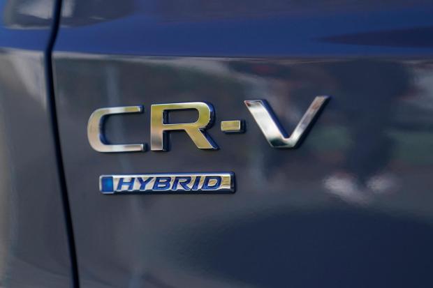 Logos are shown on the exterior of a 2024 Honda CR-V Hybrid in Sunnyvale, Calif., Monday, Dec. 11, 2023. Like many hybrid buyers, Shilander Singh, an Uber driver, said that for him, the gas savings helped tip the price equation in favor of a Honda CR-V hybrid over the corresponding gasoline model.(AP Photo/Jeff Chiu)